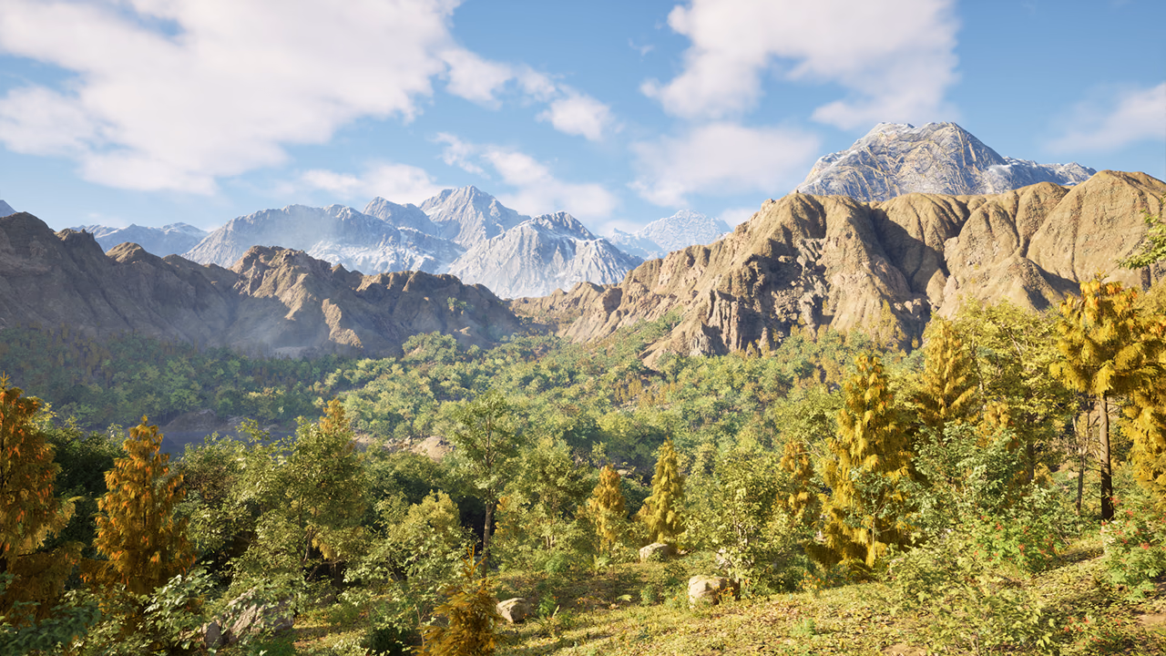 A forested mountain valley with rocky peaks beneath a blue sky.