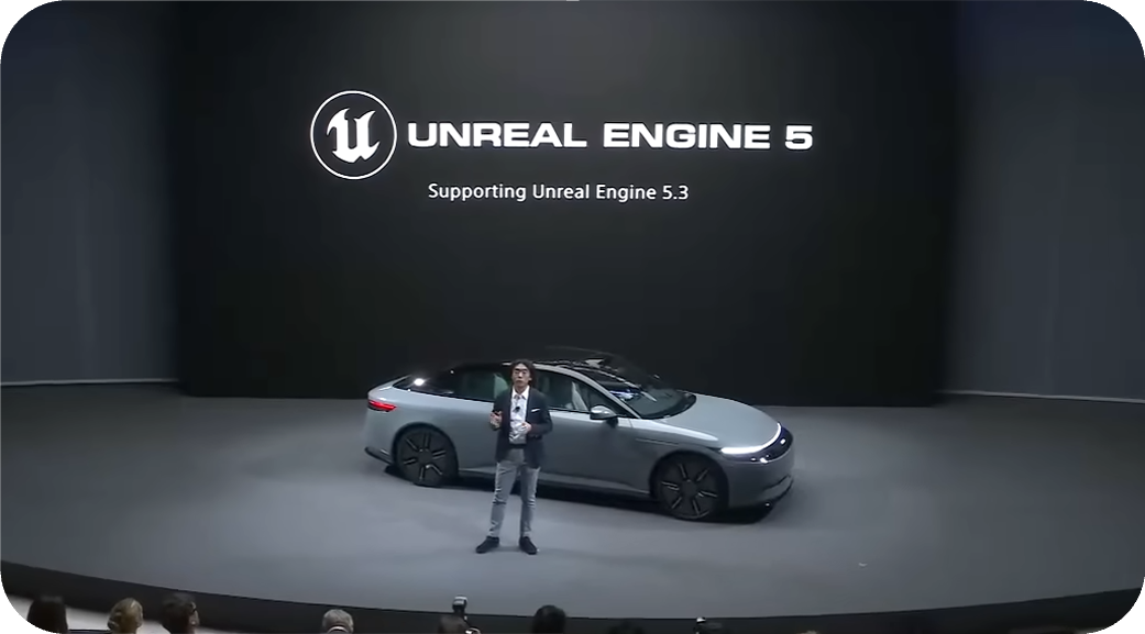 A car and presenter on a stage beneath an Unreal Engine 5 screen.